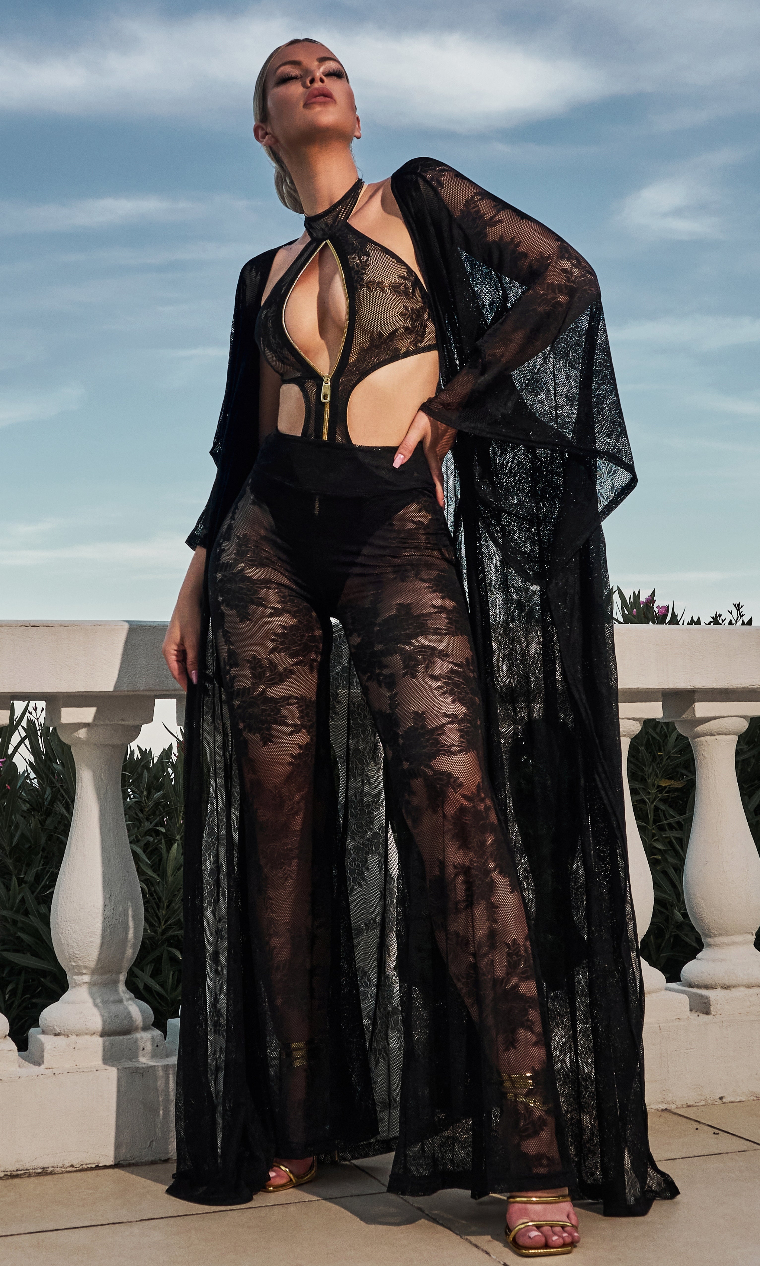 Model wearing Flora luxury sustainable sheer lace pants by Antoninias, designed with wide-leg silhouette and intricate floral detailing for premium resort wear and designer womenswear