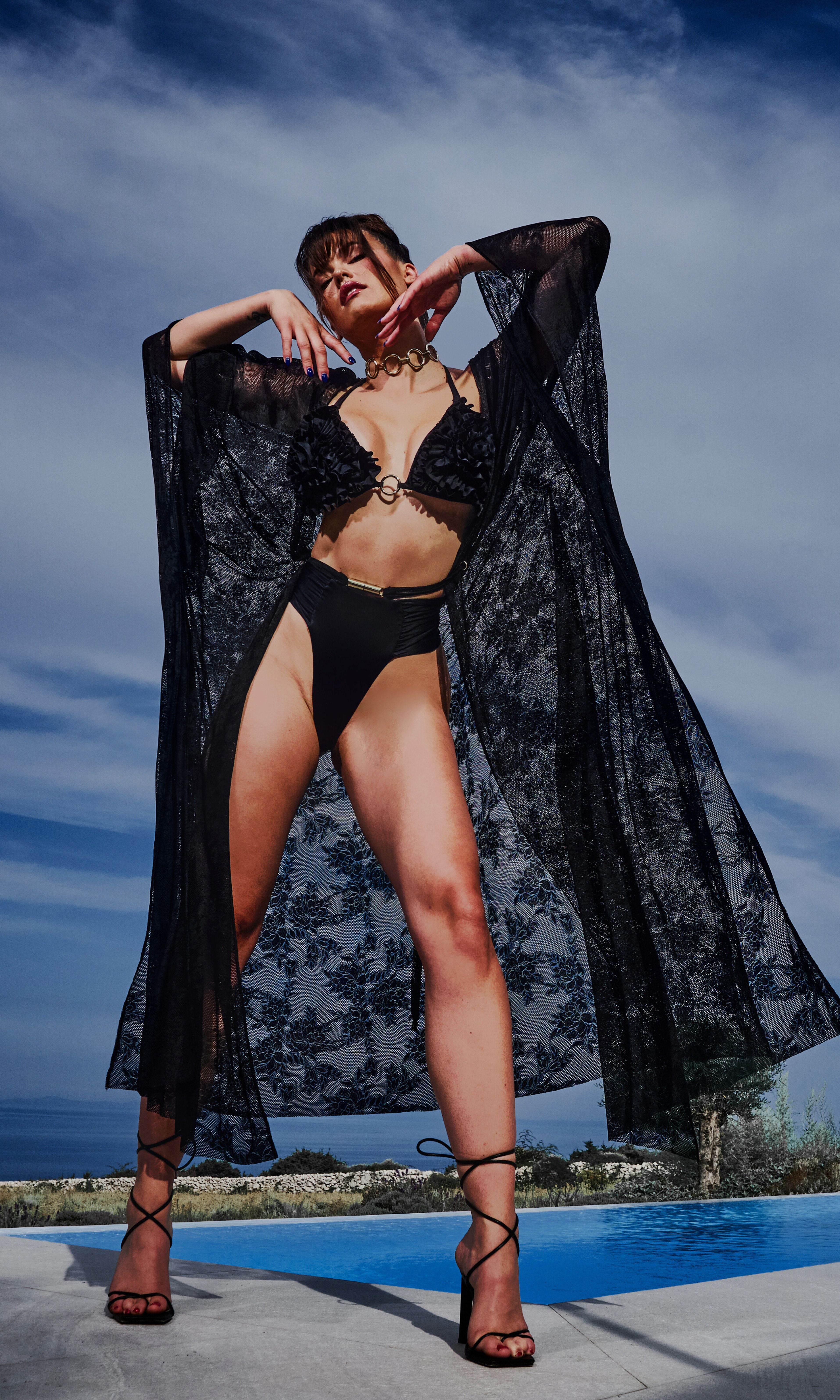 Luxury sustainable lace cover-up by Antoninias from the Flora collection, featuring sheer floral fabric, flowy silhouette, and a gold-tone belt, ideal for premium resort wear and designer womenswear.