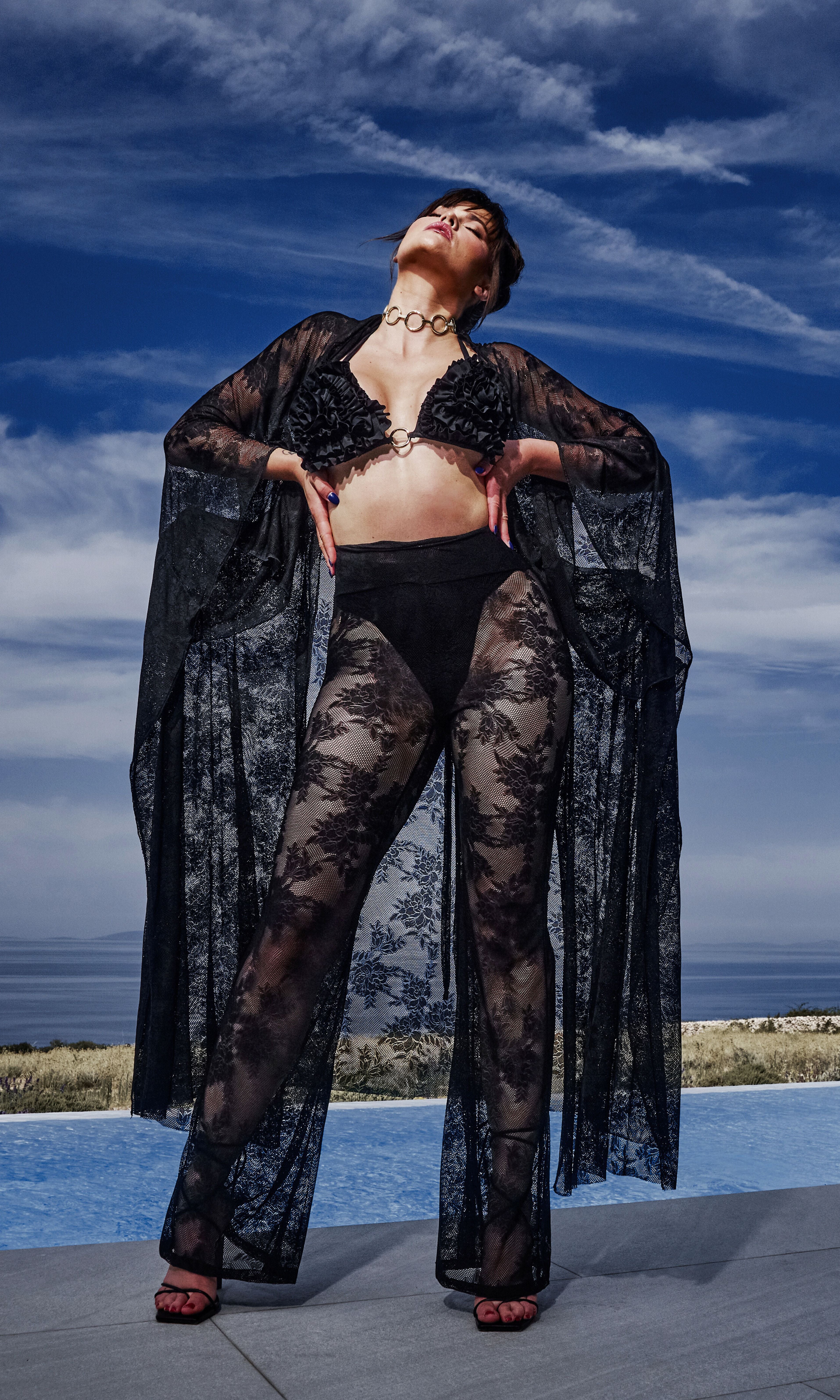 Model wearing Flora luxury sustainable sheer lace pants by Antoninias, designed with wide-leg silhouette and intricate floral detailing for premium resort wear and designer womenswear