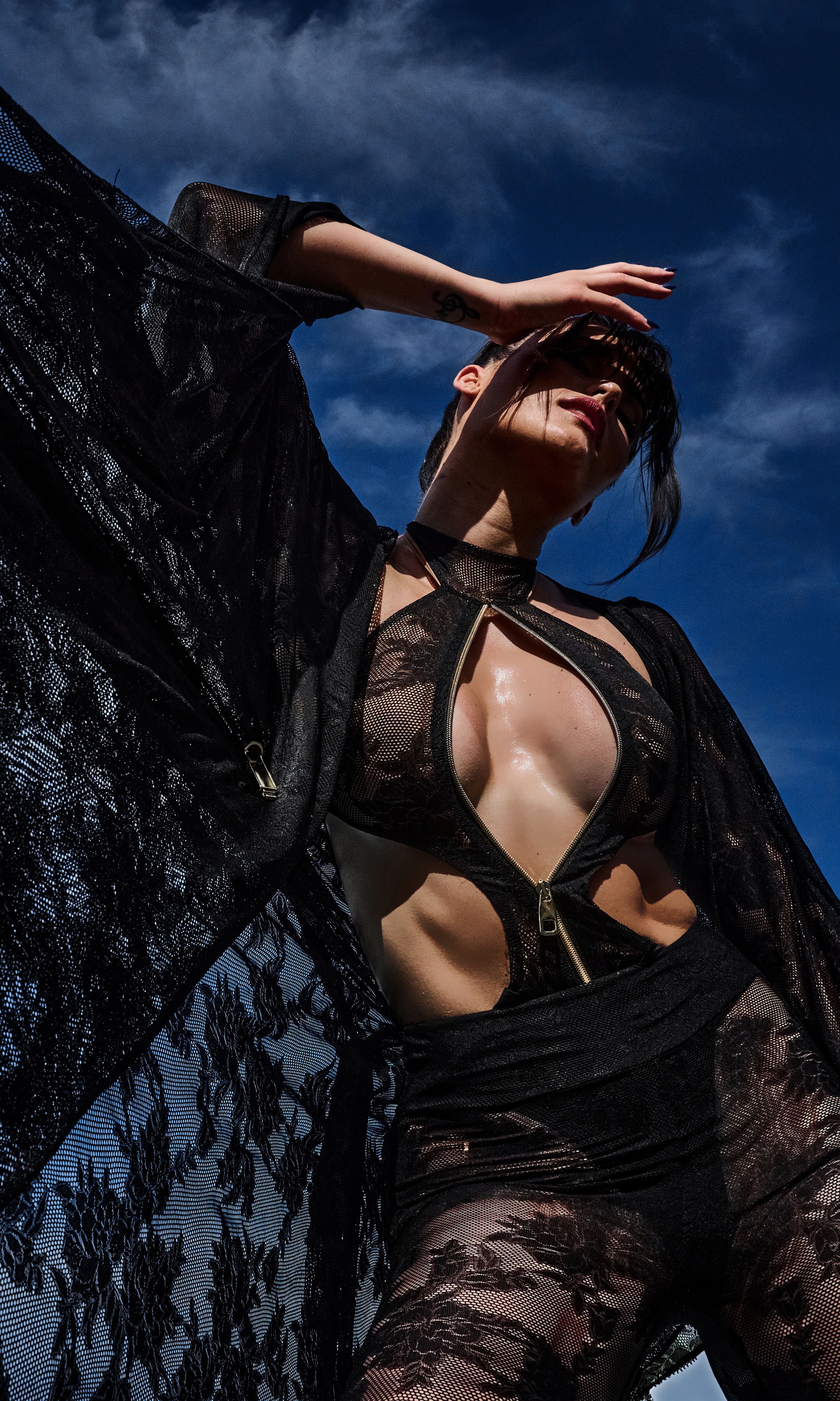 Model wearing Flora luxury sustainable one-piece swimsuit by Antoninias, featuring lace paneling, front zipper, and cut-out details, perfect for premium designer resort wear.